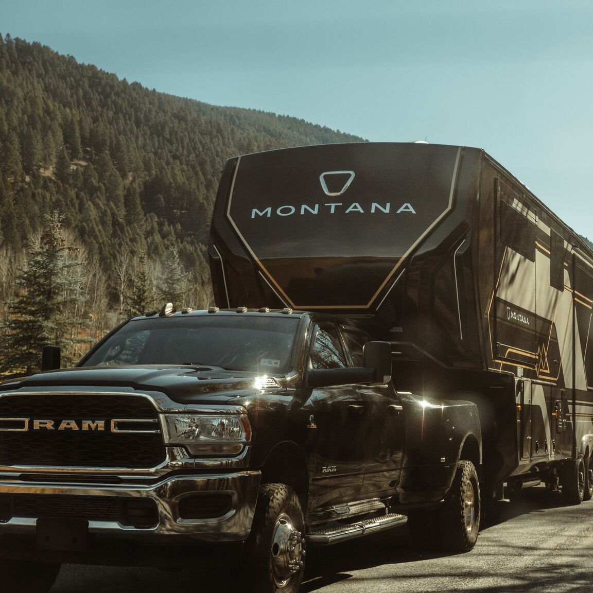 A Ram dually towing a Keystone Montana fifth wheel beside an alpine lake.